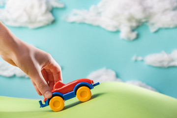 Child's hand playing with a toy car on green paper lawn