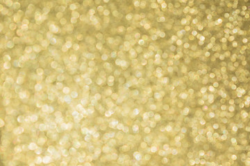 Abstract defocused background texture with golden sparkling glitter. Festive blurred backdrop for greeting cards and other design