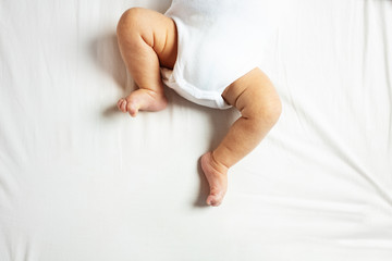 Close-up of newborn infant baby boy legs and feet laying on the back in the room