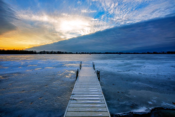 Pier in Frozen Lake at Sunset