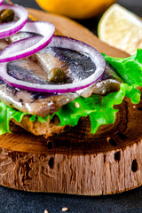 Appetizing smorrebrod with Norwegian herring, lettuce, blue onion, lemon and tomato lies on a...
