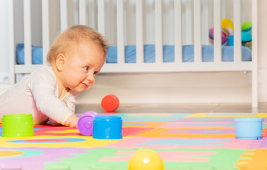 Baby toddler boy creep on the floor of nursery playing with colorful toys