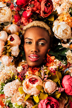 Close up beauty portrait of a beautiful young woman's face  with pink makeup surrounded with many flower blooms