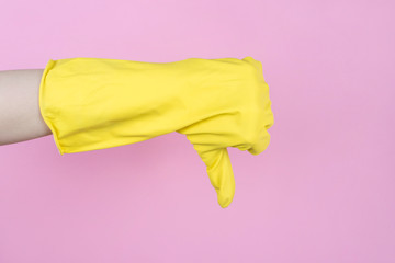 Cropped closeup side profile view photo of hand in yellow bright glove showing thumb down isolated pastel background