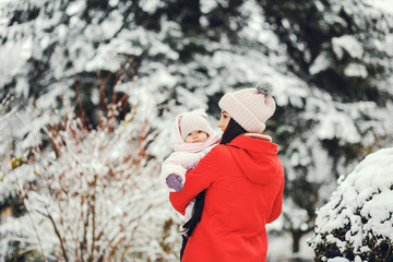 Cute family have fun in a winter park. Woman in a red jacket.