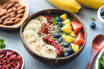 Superfood smoothie in coconut bowl with fruits and seeds toppings. Healthy eating, healthy...