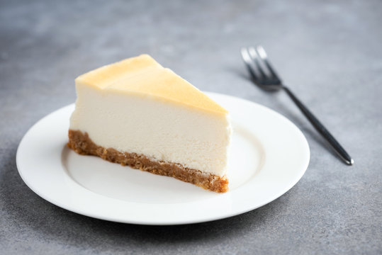 Slice of plain cheesecake on white plate and for for eating isolated on concrete background