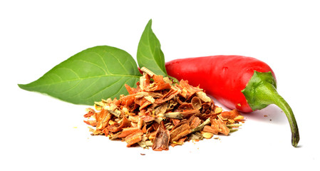 Heap of dried crushed chilli spices, fresh chilli pepper and plant leaves isolated on white background. Close-up.