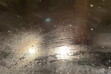 Foggy car window in snowfall winter day with traffic light and pedestrian in city road. Bad weather and storm with snowfall in city road, blur background