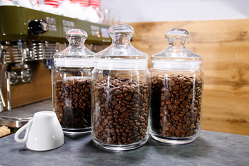 Glass bank with coffee grains costs on a table on a wood background