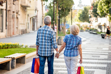 Senior couple with shopping bags walking after shopping