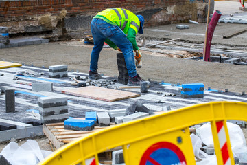 Construction work on pavement. Installation of concrete paver blocks on the sidewalk. The worker pavers pavement bricks on a pre-prepared surface of concrete mortar.