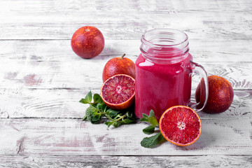 Smoothie with blood orange juice in the mason jar on the white wooden table