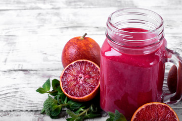 Smoothie with blood orange juice in the mason jar on the white wooden table