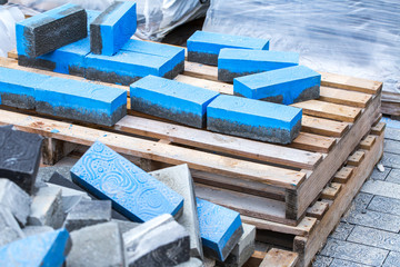 Construction work on pavement. Installation of concrete paver blocks on the sidewalk. Concrete pavement blocks lying on a wooden pallet.