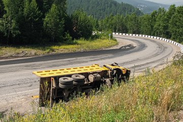 Road accident a dump truck didn't fit into sharp turn. An overturned truck on an highway in an...