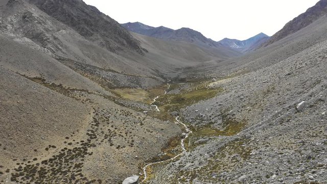 A reverse flight view inside Andes mountains at Limari Valley, south Atacama. An amazing wild scenery. Arid idyllic valleys with green farm fields feed in by the river at the bottom of the valley
