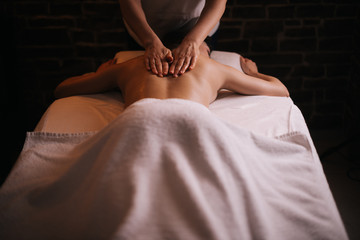 Female masseuse does back and shoulder massage to young unrecognizable woman in spa centre, close-up. Concept of luxury professional massage. Concept of body care.