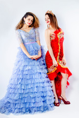 Cute young women wearing magnificent blue and red dresses. Sisters-friendly scenery. Carnival concept. Isolate
