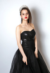 young lady posing in fashion long black dress. Individuality. Thoughtful elegant lady in a black prom dress