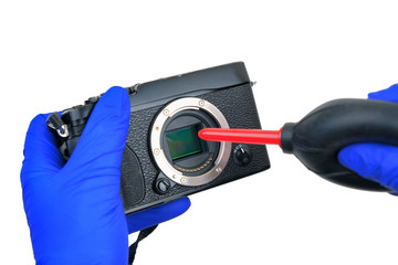 hands cleaning digital camera sensor from dust with air blower