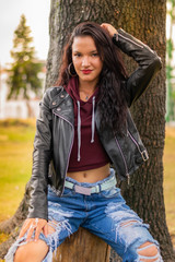 teenage Colombian woman enjoying a sunny afternoon in the city park next to a tree