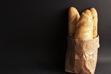 Baguette bread in brown paper bag photo isolate on black front view 