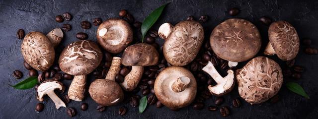 Shiitake mushrooms with coffee beans on a dark background. Top view. Coffee with mushrooms -...