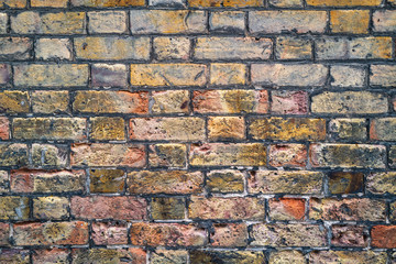 Old brick wall texture with various colours and pit marks in the bricks and mortar.