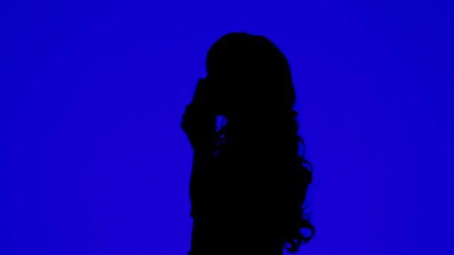 Silhouette of a woman talking on a cell phone on a blue background.
