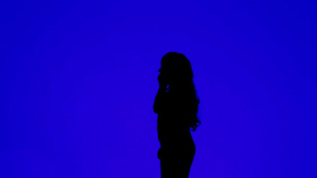 Silhouette of a woman with curly hair talking on a cell phone on a blue background