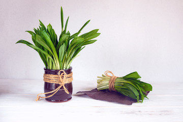 Bouquet of green leaves of wild garlic in a brown clay jar on a white background. Allium ursinum is rich in vitamins. Medicinal plant for the prevention of diseases and increase immunity. Super food.