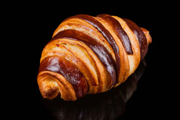  Delicious fresh chocolate croissant on a black background. Close-up.