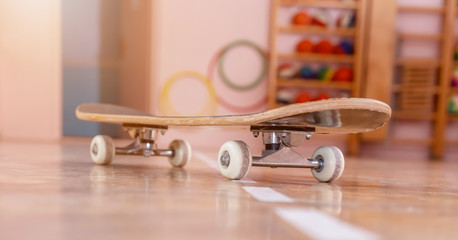 new skateboard stands on wooden parquet against various blurry toys in children room
