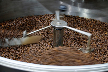 The freshly roasted coffee beans from a large coffee roaster being poured into the cooling...