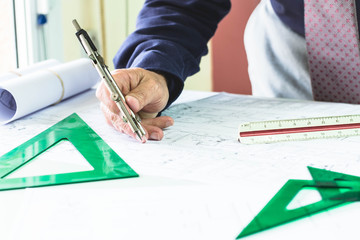 Architect with blue shirt and tie with a compas in his hand tracing on a plane © valebenifer