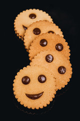  Delicious cookies in the form of funny emoticons. Black background. Top view.