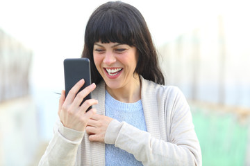 Fototapeta premium Adult woman laughing checking smart phone content