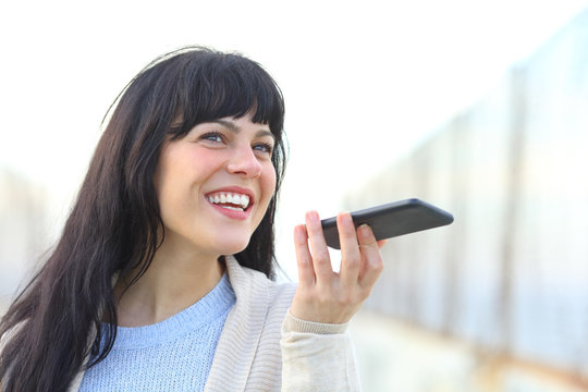 Happy woman messaging using voice recognition on phone