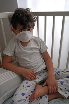 Italy , Milan - European white boy children quarantine with mask sleeping in bed of the house - contagion of the Novel Coronavirus 2019- ncov -  virus incubation isolation   
