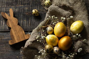 Easter eggs on wooden background. Gold handmade easter eggs in a basket.