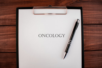 Word oncology: text written on a shit of paper of notebook on the wooden background. Medical concept.