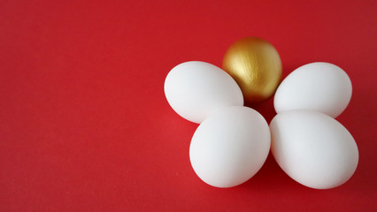Golden and white eggs lie on a red background. Happy easter concept, copy space.