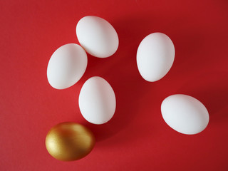 Golden and white eggs lie on a red background. Happy easter concept, top view.