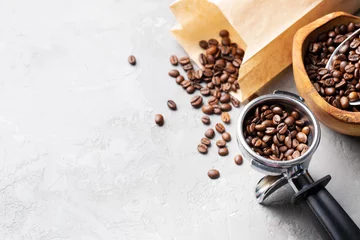 Selbstklebende Fototapeten Cafe Kaffeebohnen in einer Holzschale aus Olivenholz, in einer Papiertüte und einem Metall-Siebträger auf hellgrauem Hintergrund. Platz für Text.  © Eirene Fagus