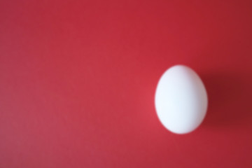 White egg lie on a red background. Happy easter concept, top view, copy space.
