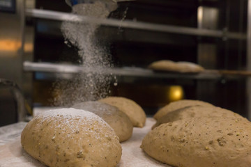 Pouring flour to the bread loafs before entering them in the oven