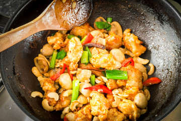 Chicken and cashew nuts being cooked in a wok