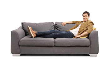 Casual young man lying on a sofa and smiling at the camera