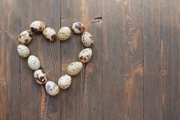 Quail eggs in a shape of heart on a wooden background and checkered napkin